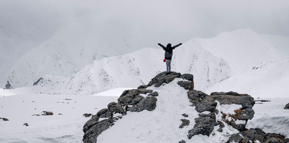 Kashmir Tour Package 5N-6D @13,999 Book Now 1 In Kashmir tour package, a tourist is enjoying the snowfall in Kashmir with both his hands raised.